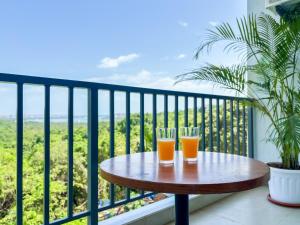 Dois copos de sumo de laranja sentados numa mesa na varanda. em 2BHK apartment with River Views l 5 star Vibes em Porvorim