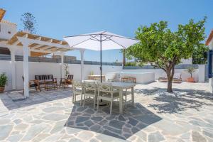 a patio with a table and an umbrella at Koula's Aegina in Perdhika