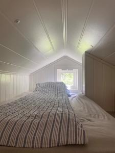 a large bed in a white room with a window at Koselig hytte nær sandstrand in Langenes