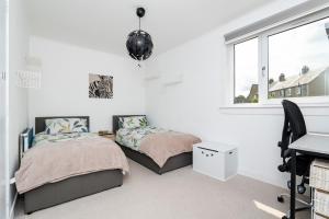 ピーブルスにある3 Bed House-Free Parkingのデスク、窓が備わるドミトリールームのベッド2台分です。