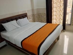a bedroom with a bed with an orange and white blanket at Via Sagar Residency in Navi Mumbai +4 photos