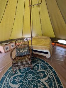 a bedroom with a bed and a chair in a tent at Belltent La Jonquille in Hurecourt