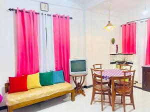 a living room with colorful curtains and a table with a television at Green Bird Villa in Dickwella