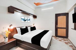 a bedroom with a bed with a black and white comforter at HOTEL O 4 SQUARE A LUXURY ROOMS NEAR RDC MAIN MARKET in Ghaziabad