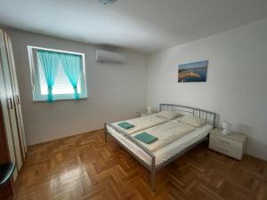 a bedroom with a bed and a window at Kristina Apartmanház in Dobrinj