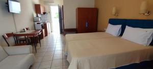 a bedroom with two beds and a table and a kitchen at Amalia in Paleo Tsifliki