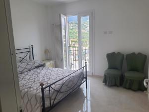 a bedroom with a bed and two green chairs at Casa Ponente in Sanremo
