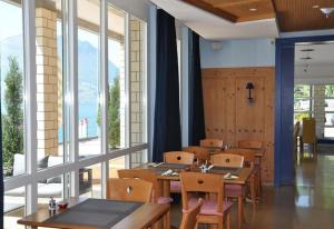 a restaurant with wooden tables and chairs and windows at Gersau Hotel Fähri in Gersau