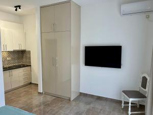 a white kitchen with a tv on a wall at Casa M- Studio #1 - Brand New in Herceg-Novi
