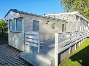 a tiny house with a wooden ramp and a fence at Hollender Pool & Chill House Sarbinowo in Sarbinowo