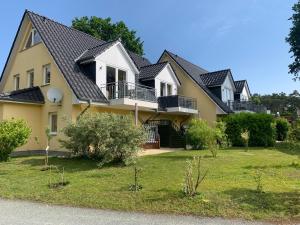 ein großes gelbes Haus mit einem schwarzen Dach in der Unterkunft Family Apartments Tom in Ostseebad Karlshagen