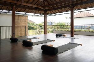 a yoga class with black mats on a wooden floor at Rasa Ubud Yoga Coliving in Ubud