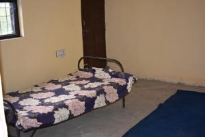 un petit lit dans une chambre avec une couette fleurie dans l'établissement sainkietan, à Jāmb
