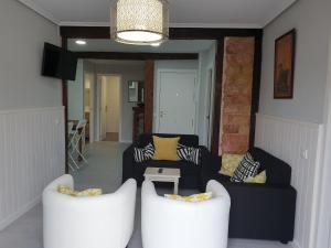 a living room with two white chairs and a couch at Alojamientos el Paramo in San Vicente de la Barquera