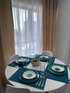 a white table with blue plates and silverware on it at Olimp sea view apartments - 802 in Olimp
