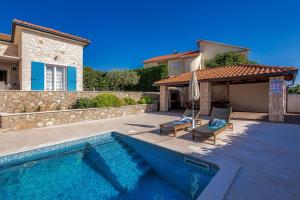 a pool with two chairs and an umbrella next to a house at Villa Augusta in Malinska
