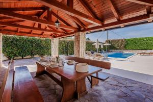 a wooden dining table in a patio with a pool at Villa Augusta in Malinska +33 photos