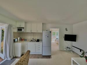 a kitchen with white cabinets and a refrigerator at Studio 35 Kerikeri in Kerikeri