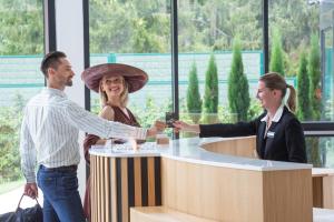 a man and a woman shaking hands at a counter at 6717 Nature Hôtel & Spa Le Clos des Délices in Ottrott +87 photos