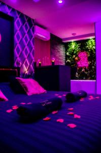 a purple room with a bed with pink lighting at Le secret des déoux love room in Forcalqueiret
