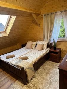 a large bed in a wooden room with windows at PodKarpackim Niebem Jaśliska in Jaśliska