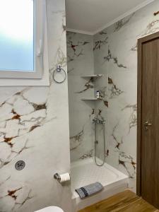 a bathroom with a shower with white marble walls at Alexas Apartment in Myrina +16 photos