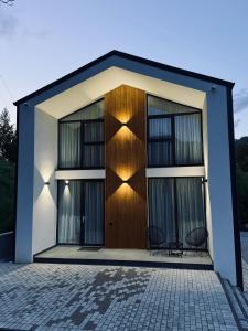 ein Haus mit einer Holztür und zwei Stühlen davor in der Unterkunft Cozy HillSide in Borşa