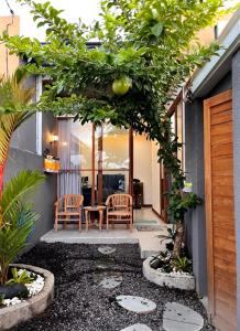 un patio con 2 sillas, una mesa y árboles en Villa Teras Asri Seminyak, en Denpasar