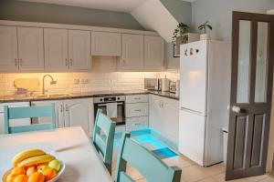 a kitchen with white cabinets and a table with a bowl of fruit at Cozy Home at Ebrington Square in Derry Londonderry