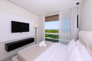a white bedroom with a large window and a television at Royal Suite Caesarea in Caesarea +140 photos