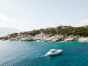 a boat in the water next to an island at Emelisse Nature Resort in Fiskardho