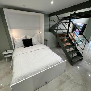 a bedroom with a white bed and a staircase at Maison au bord de la plage - Bottaï in Port-de-Bouc