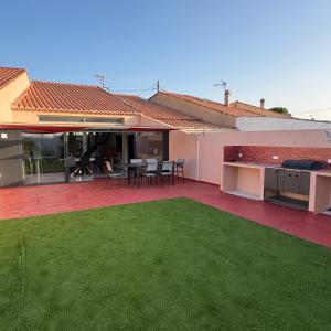a patio with a lawn in front of a house at Maison au bord de la plage - Bottaï in Port-de-Bouc
