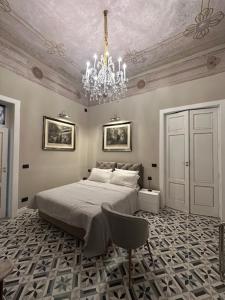 Un dormitorio con una cama y una lámpara de araña. en Residenza d'epoca Palazzo Raffaele alla Maggiore, en Lamezia Terme