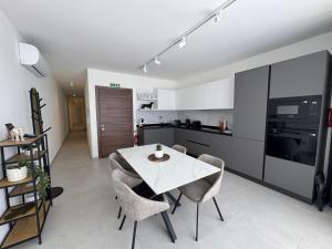 a kitchen and dining room with a white table and chairs at Top Floor Penthouse with Valletta Views & Terrace in Gwardamanġa