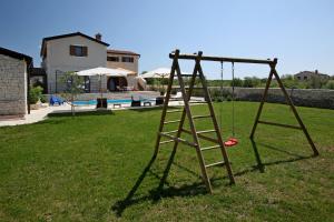 a swing set in a yard next to a house at Villa Histra in Čabrunići