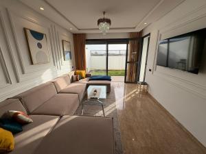 Una sala de estar con un sofá y un televisor en Bain de soleil à Dar Bouazza, en Dar Bouazza