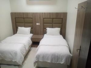 two beds with white sheets in a room at سمو الخير in Haradh Camp