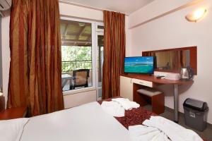 a hotel room with a bed and a desk and a television at Guesthouse Kirov in Ravda