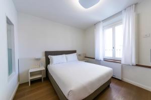 a white bedroom with a bed and a window at Arona Palace in Arona