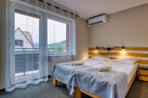 two beds in a room with two large windows at Ada in Muszyna