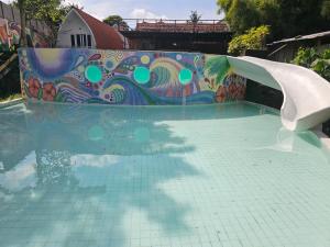 a water slide in a pool with a mosaic wall at Cove Wong Village in Tumbak Bayuh