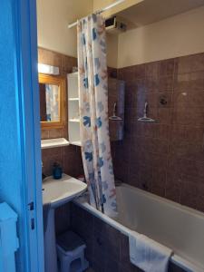 a bathroom with a sink and a tub and a shower curtain at Studio vue mer - La Turballe in La Turballe