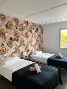 two beds in a bedroom with a floral wallpaper at Sea Lovers Apartment in Alcudia