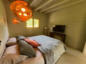 a bedroom with a bed and a window and a chandelier at Coeur Cévennes Wooden Cottage in Camprieu