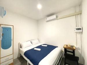 a small bedroom with a bed with a blue blanket at Moon Pīti in Bangkok