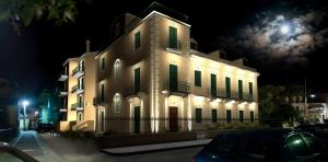 un grand bâtiment blanc avec des fenêtres aux volets verts la nuit dans l'établissement Luxury Bay View, à Corfou