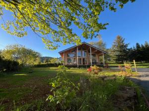 a cabin in the middle of a grassy field with a tree at Coeur Cévennes Wooden Cottage in Camprieu +17 photos