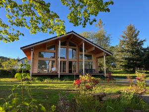 a house with large glass windows on a lawn at Coeur Cévennes Wooden Cottage in Camprieu