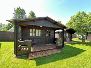 a wooden cabin with a deck in the grass at Rendixime - Karjamaa Garden Bungalows Free parking and coffee in Pärnu +20 photos